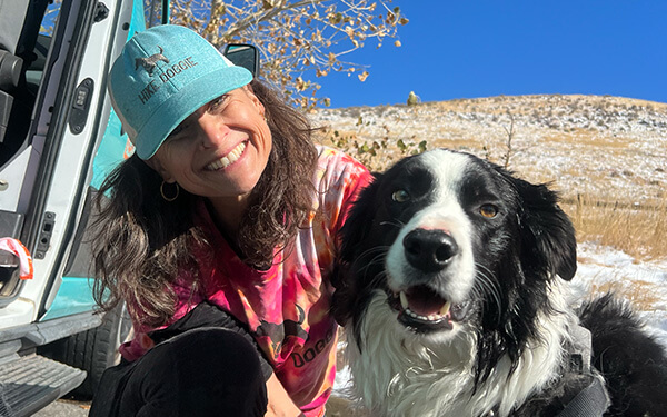Woman hugging black and white collie on trail