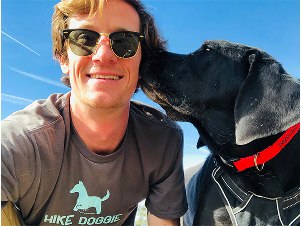 Staff member taking selfie with black dog outdoors
