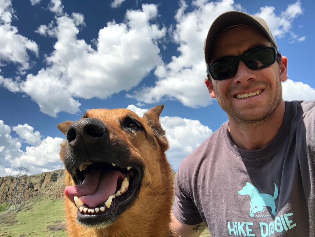 Man smiling with brown dog selfie, happy hiking moment