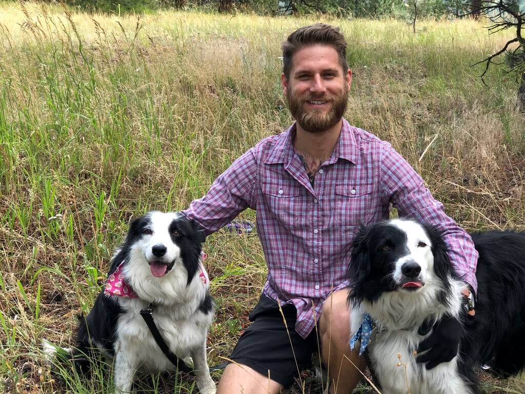 Man sitting with two border collies, calm pack portrait
