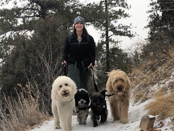 Woman standing with three dogs on leash in wooded park