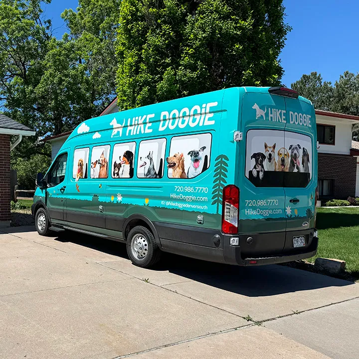 Teal dog hiking van parked in driveway, mobile service vehicle