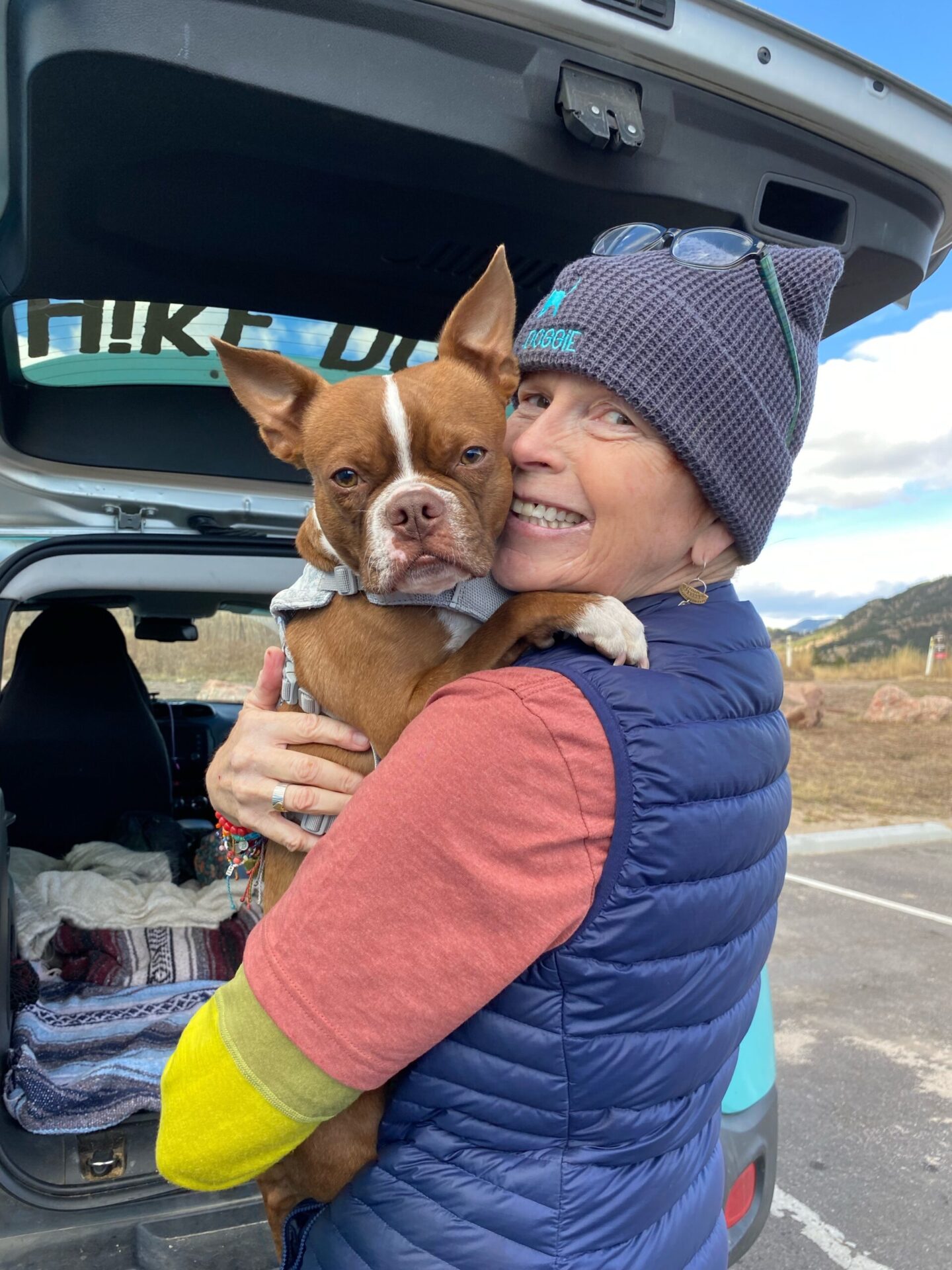 Handler hugging small dog beside Hike Doggie van