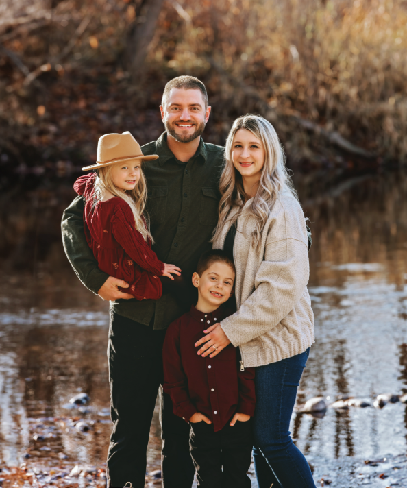 Family portrait outdoors with parents, child, and dog